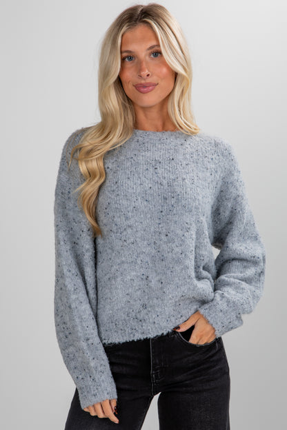 Woman wearing a gray sweater against a plain background