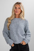 Woman wearing a gray speckled sweater against a plain background
