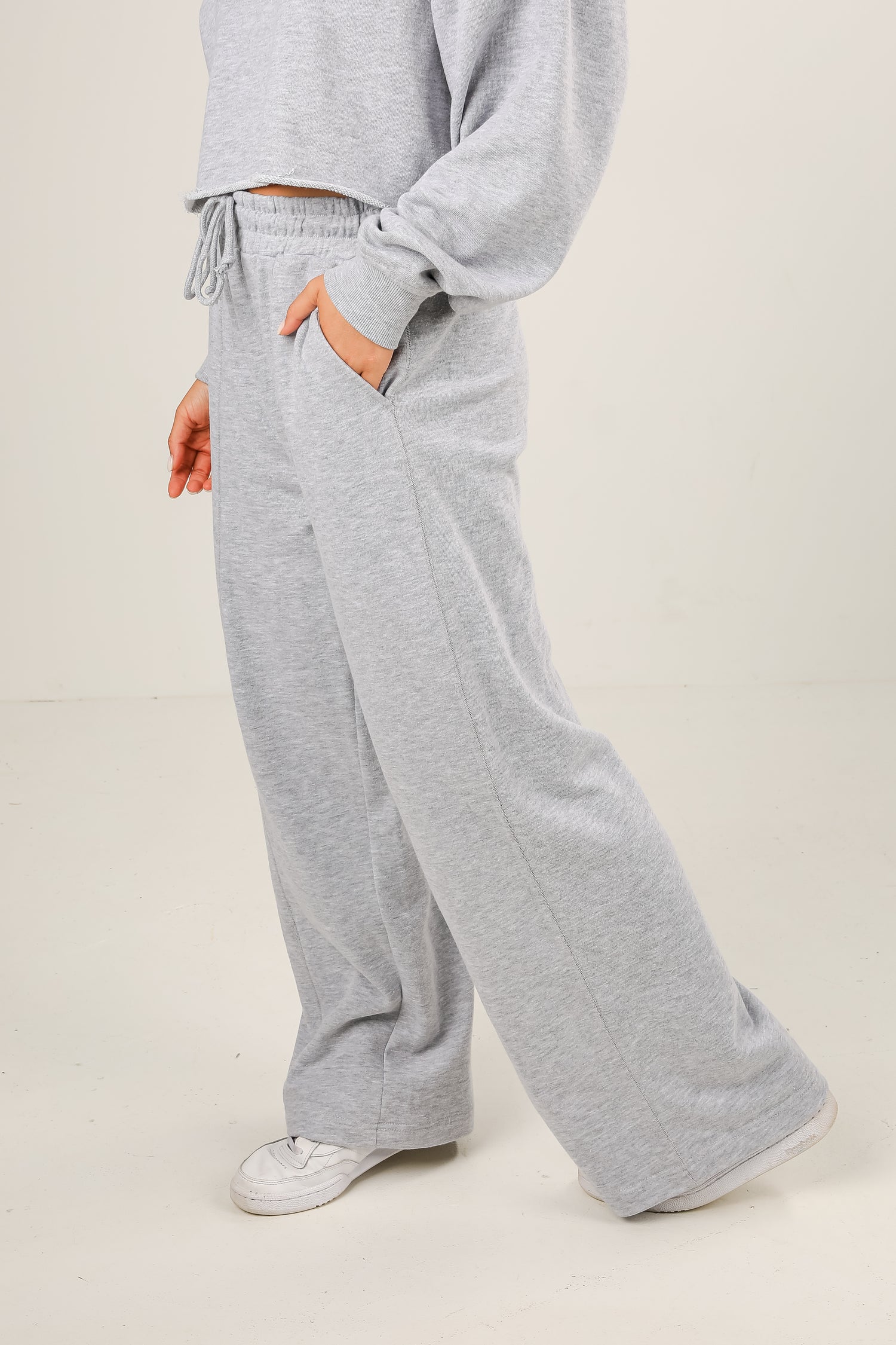 Person wearing gray sweatpants and a matching top on a plain background