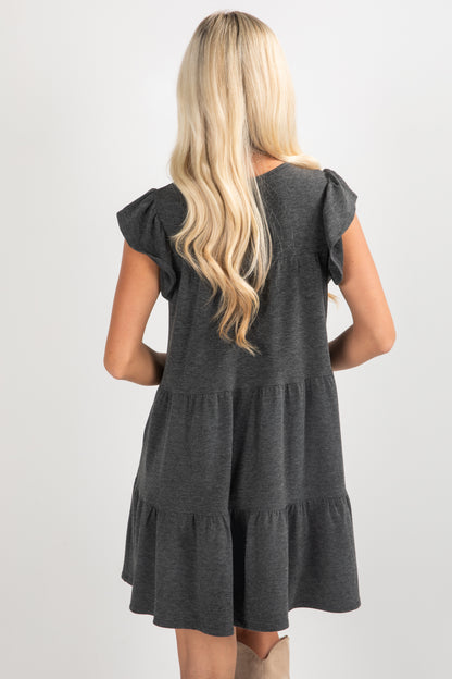 Woman wearing a gray dress with ruffled sleeves on a white background