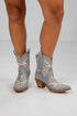Gray embroidered cowboy boots worn by a person on a white background