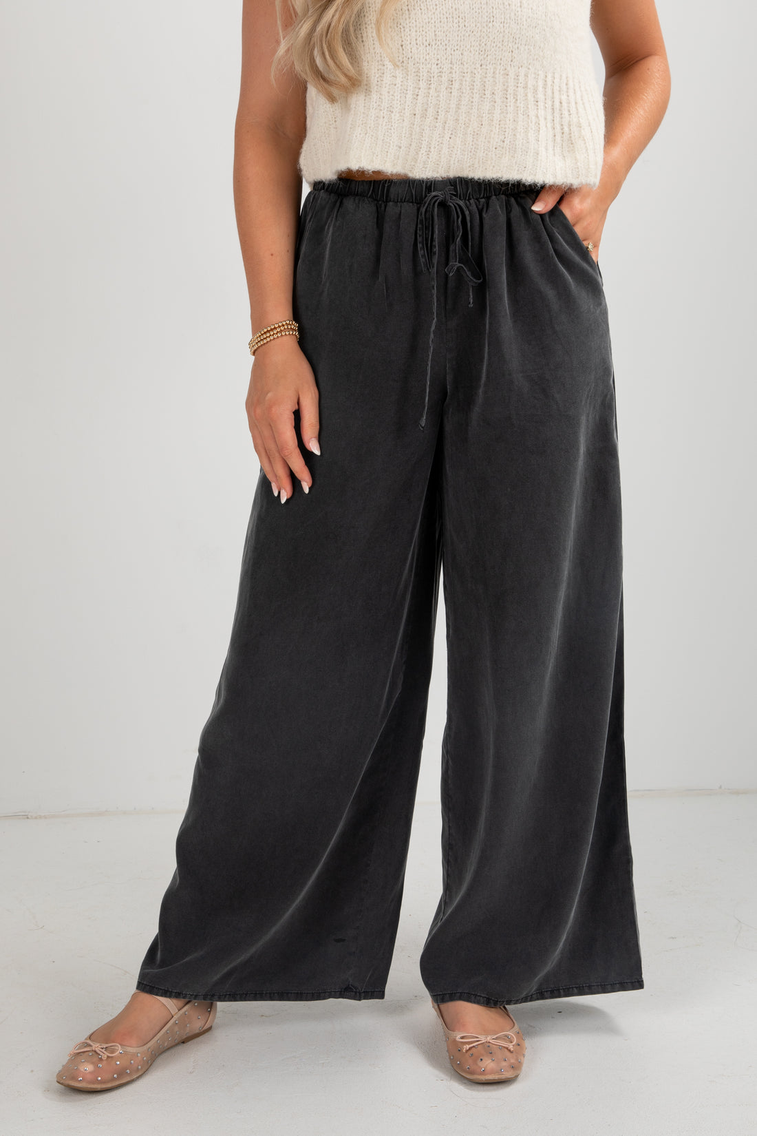 Person wearing black wide-leg pants with a white background