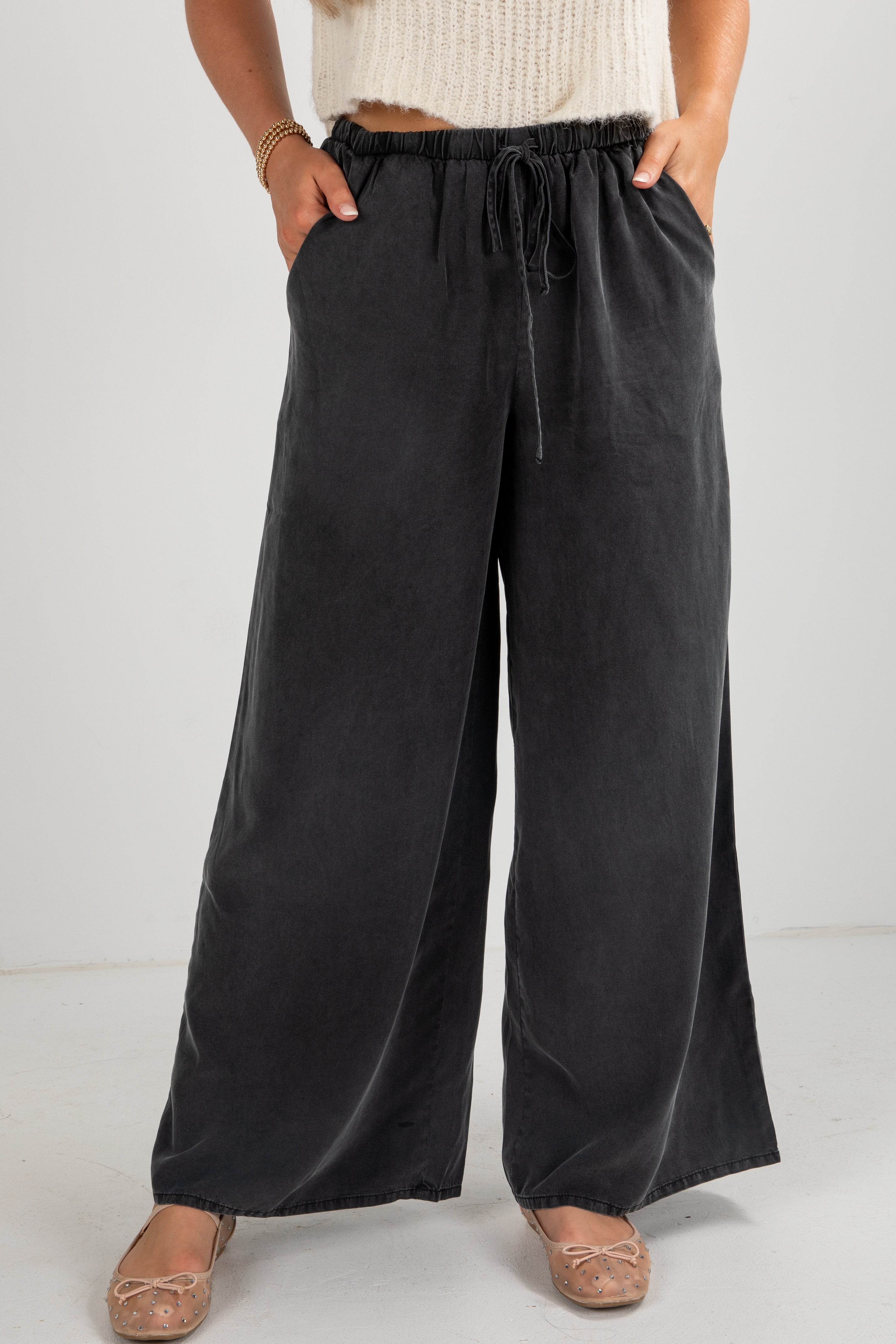 Person wearing black wide-leg pants with a white background