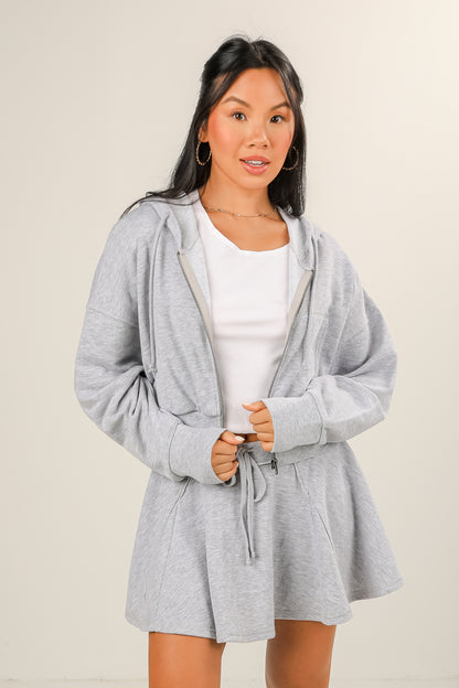 Woman wearing a gray robe over a white shirt on a beige background