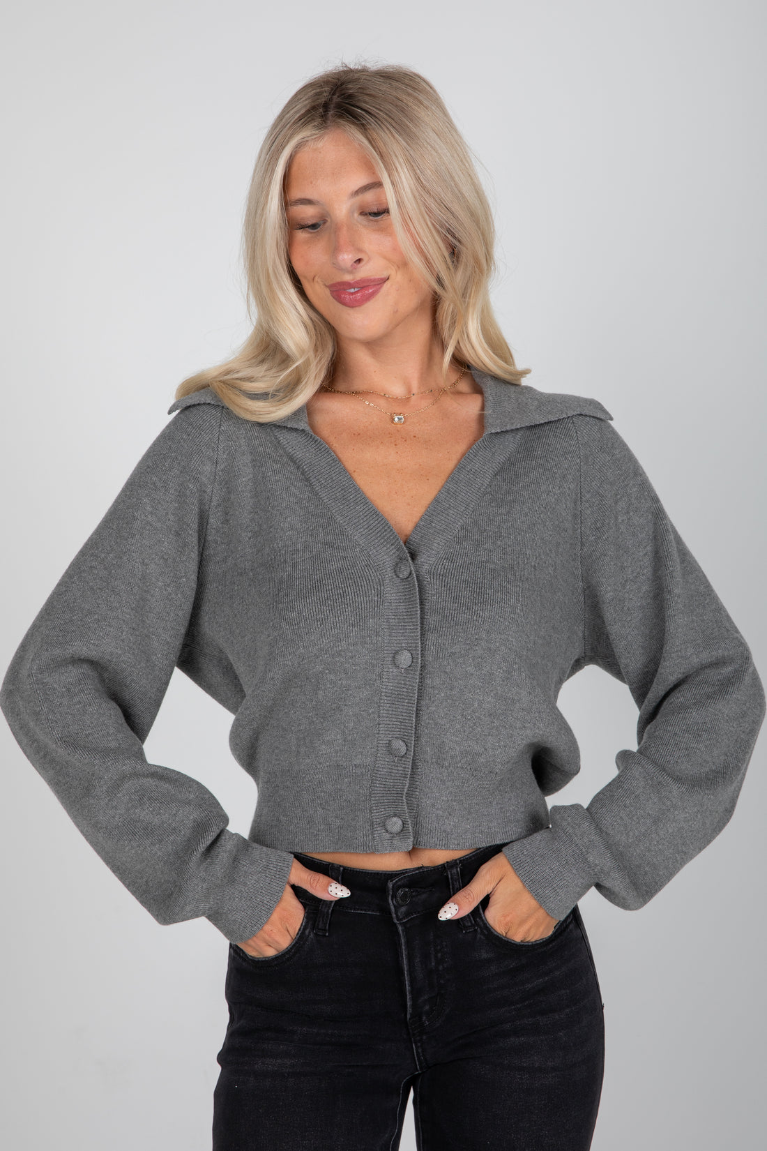 Woman wearing a gray cardigan against a plain background