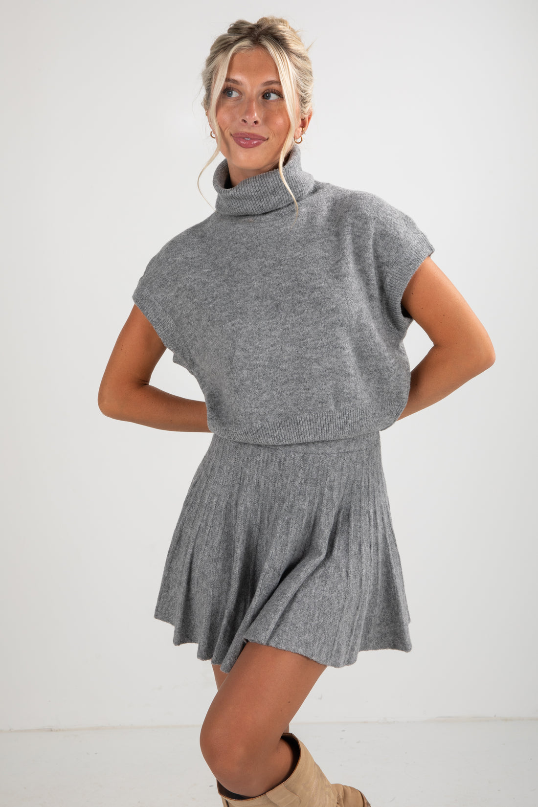Woman wearing a gray knit dress with a cowl neck on a white background