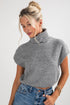 Woman wearing a gray knit top and blue jeans on a white background