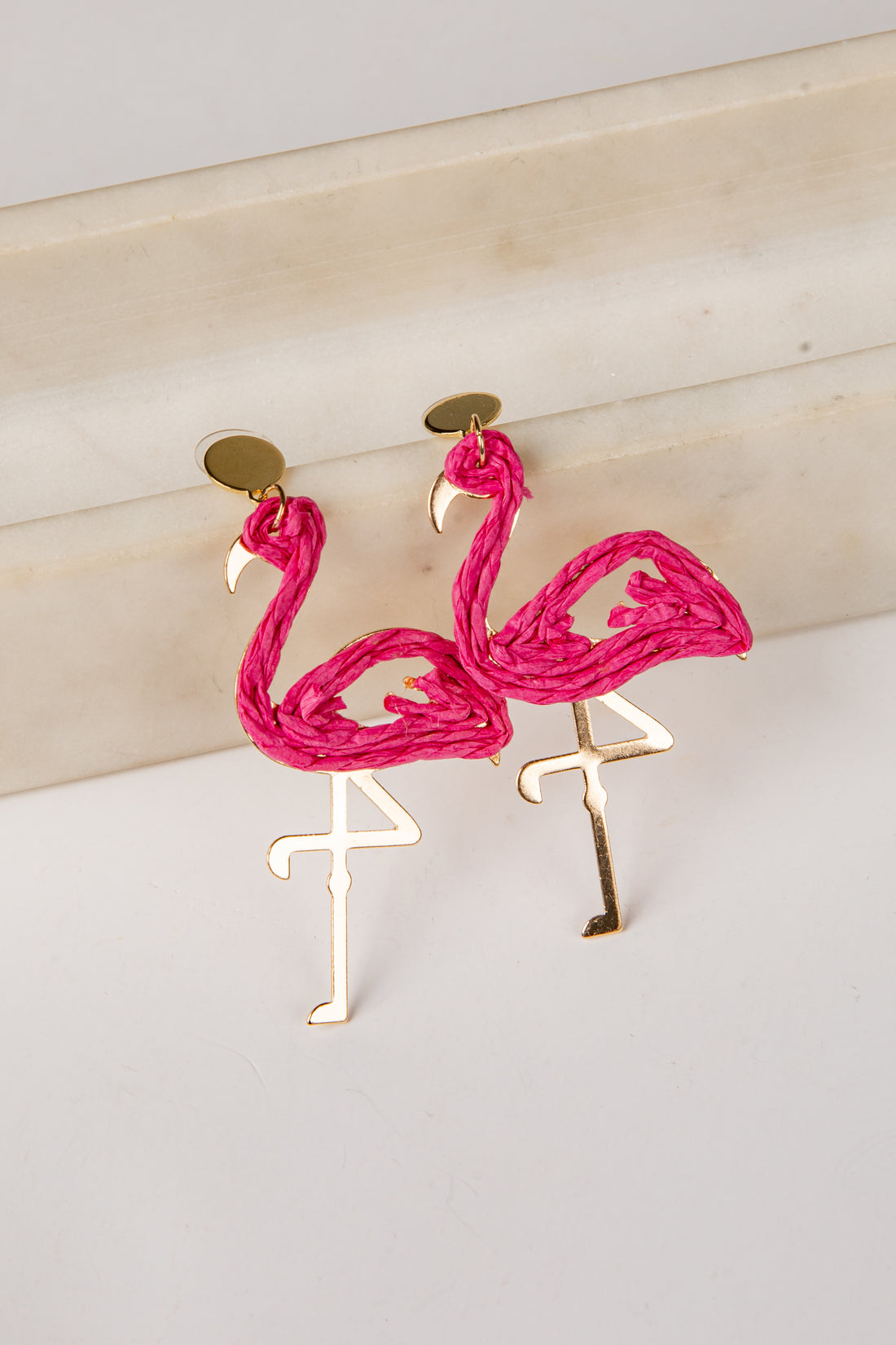 Flamingo-shaped earrings on a light wooden surface