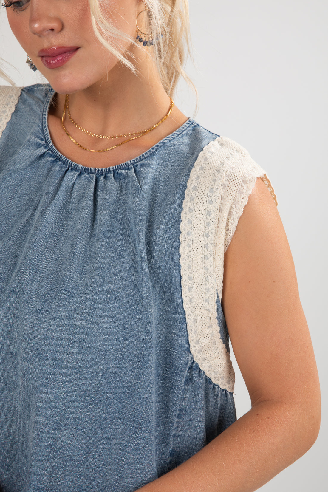 Woman wearing a blue dress with lace sleeves on a light gray background