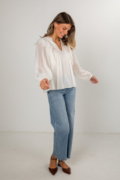 Woman wearing a white blouse and blue jeans against a white background