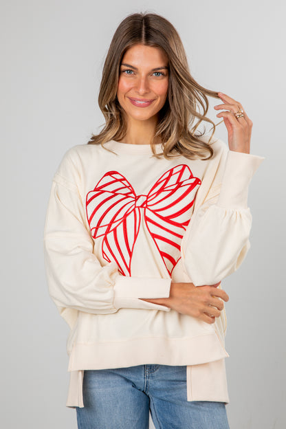 Woman wearing a cream sweater with a red heart design on a gray background