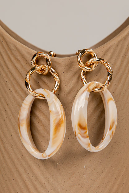 Pair of gold hoop earrings with marbled beige and brown stones on a beige surface.