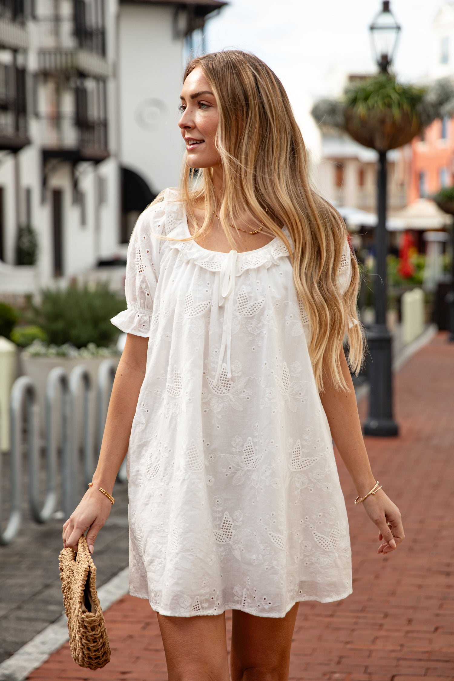 Woman in a white lace dress walking on a street.