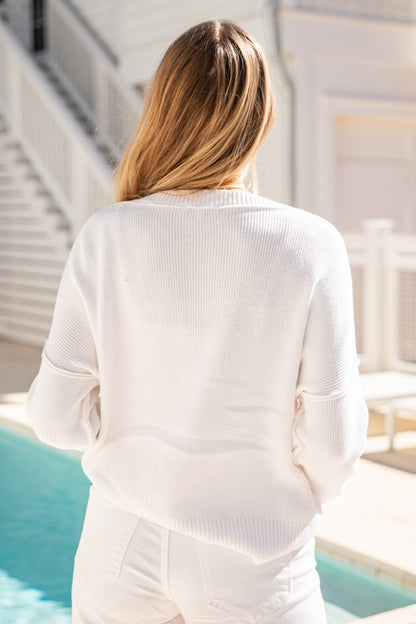 Person wearing a white outfit by a poolside with a neutral background