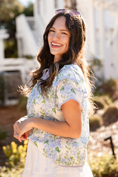 Woman in a floral dress standing outdoors with a blurred background