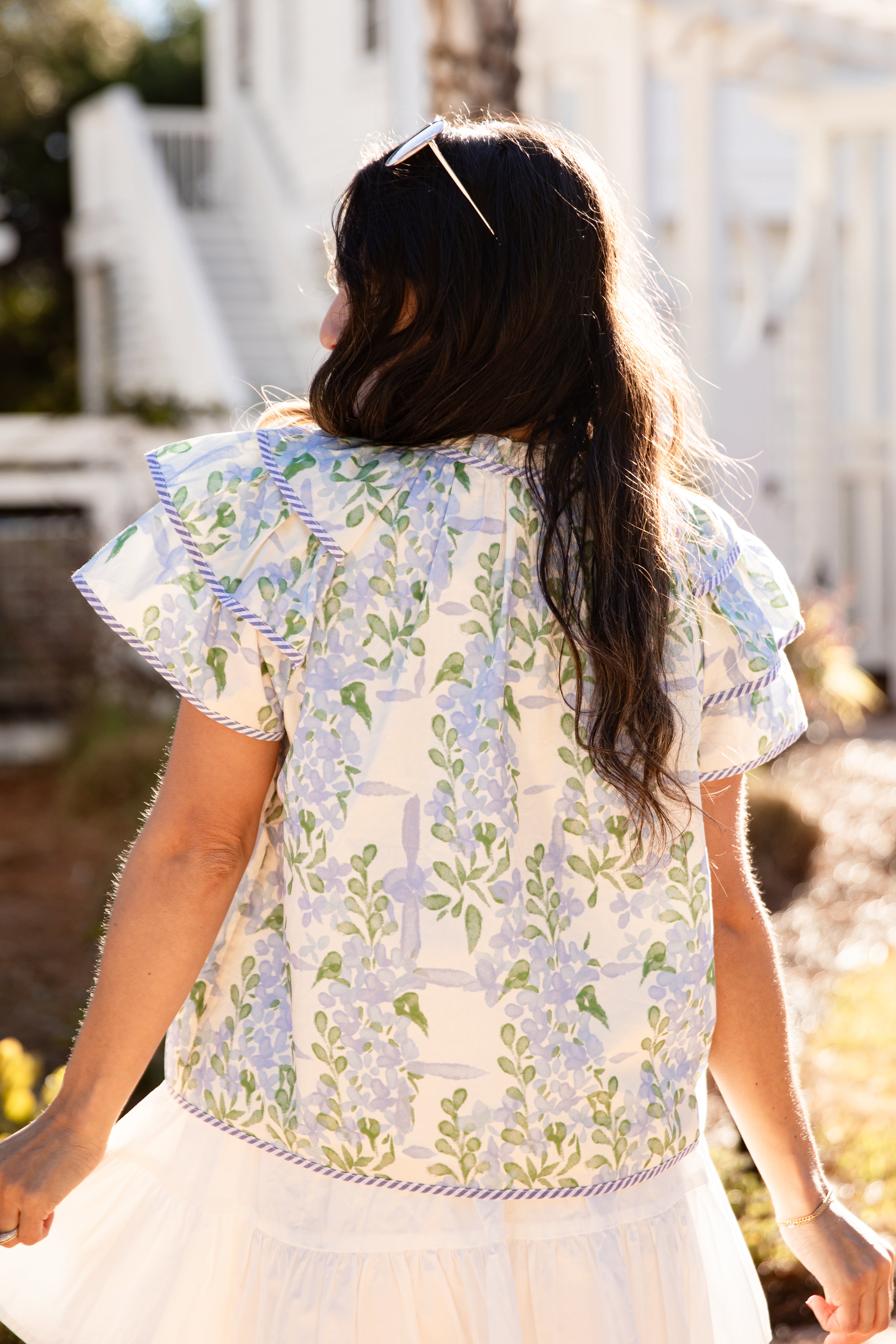 Woman wearing a floral blouse and white skirt outdoors