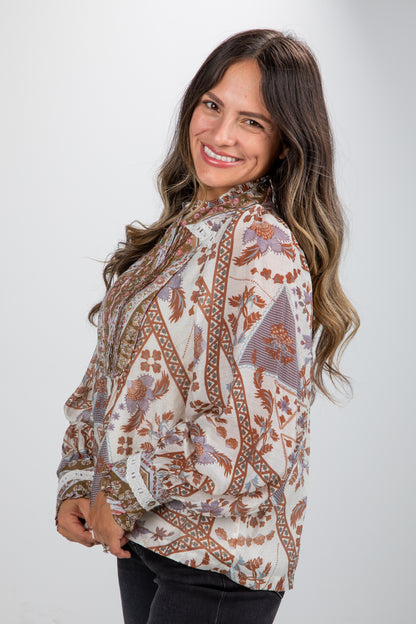 Woman wearing a patterned blouse against a plain background