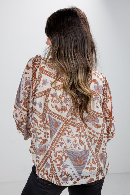 Person wearing a patterned blouse with a white background