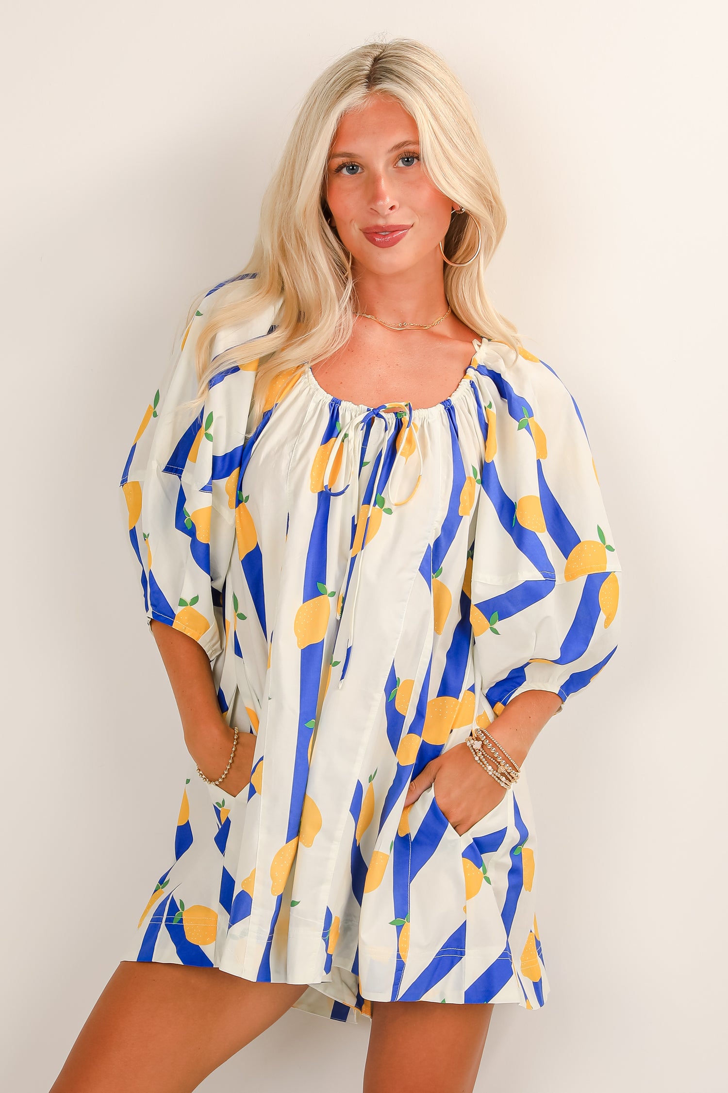 Woman wearing a patterned dress with blue and yellow accents on a plain background