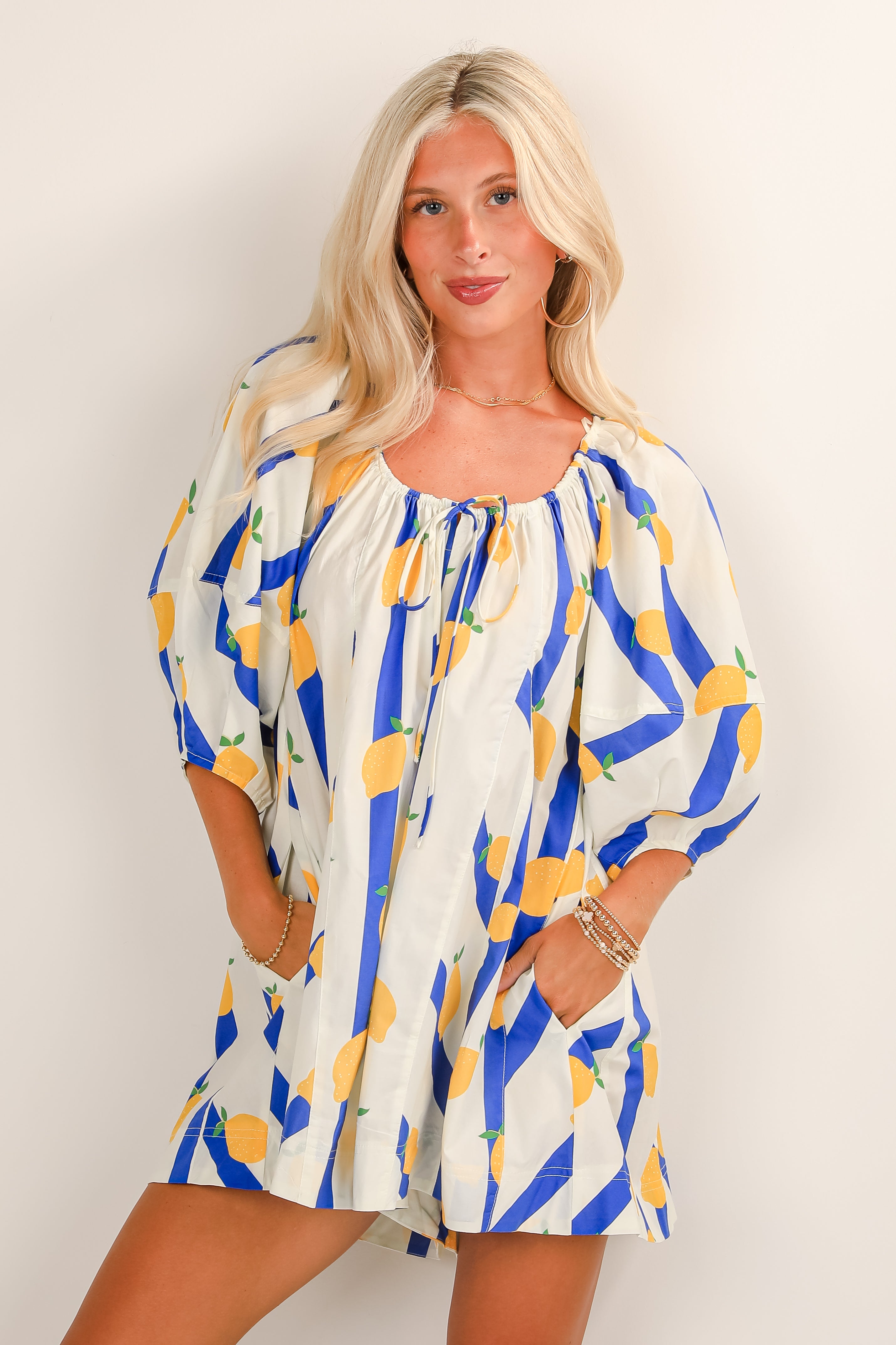 Woman wearing a patterned dress with blue and yellow accents on a plain background