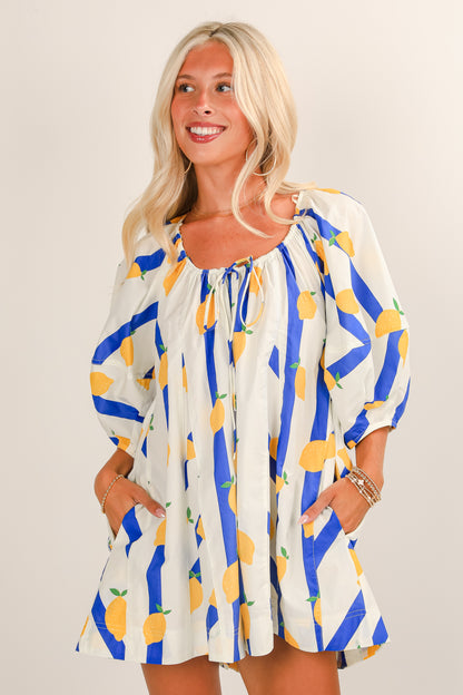 Woman wearing a colorful dress with lemon pattern on a plain background