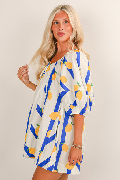 Woman wearing a dress with lemon and blue stripe pattern on a plain background