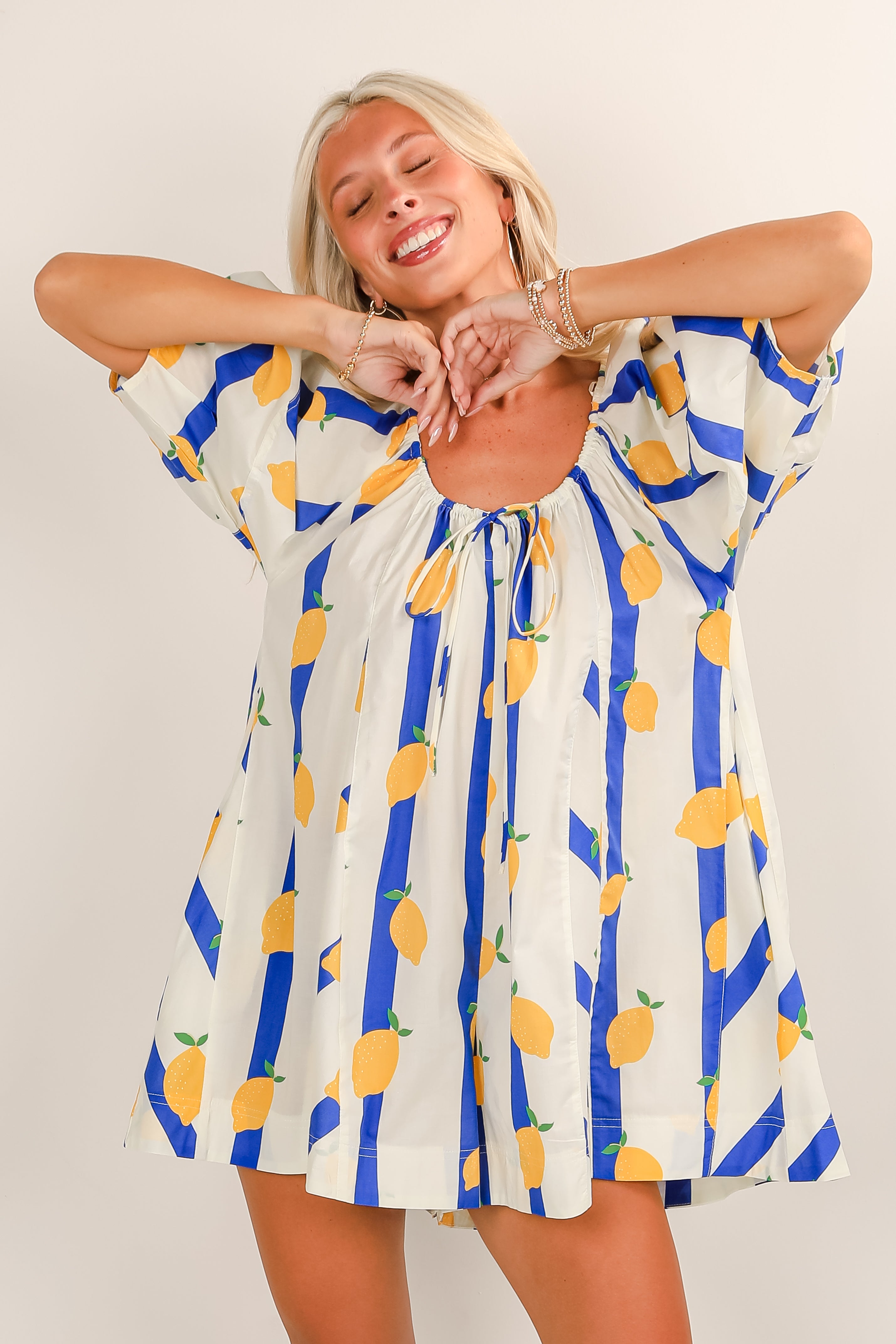 Woman wearing a dress with lemon and striped pattern on a plain background
