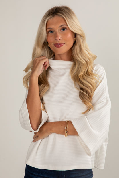 Woman wearing a white sweater against a plain background