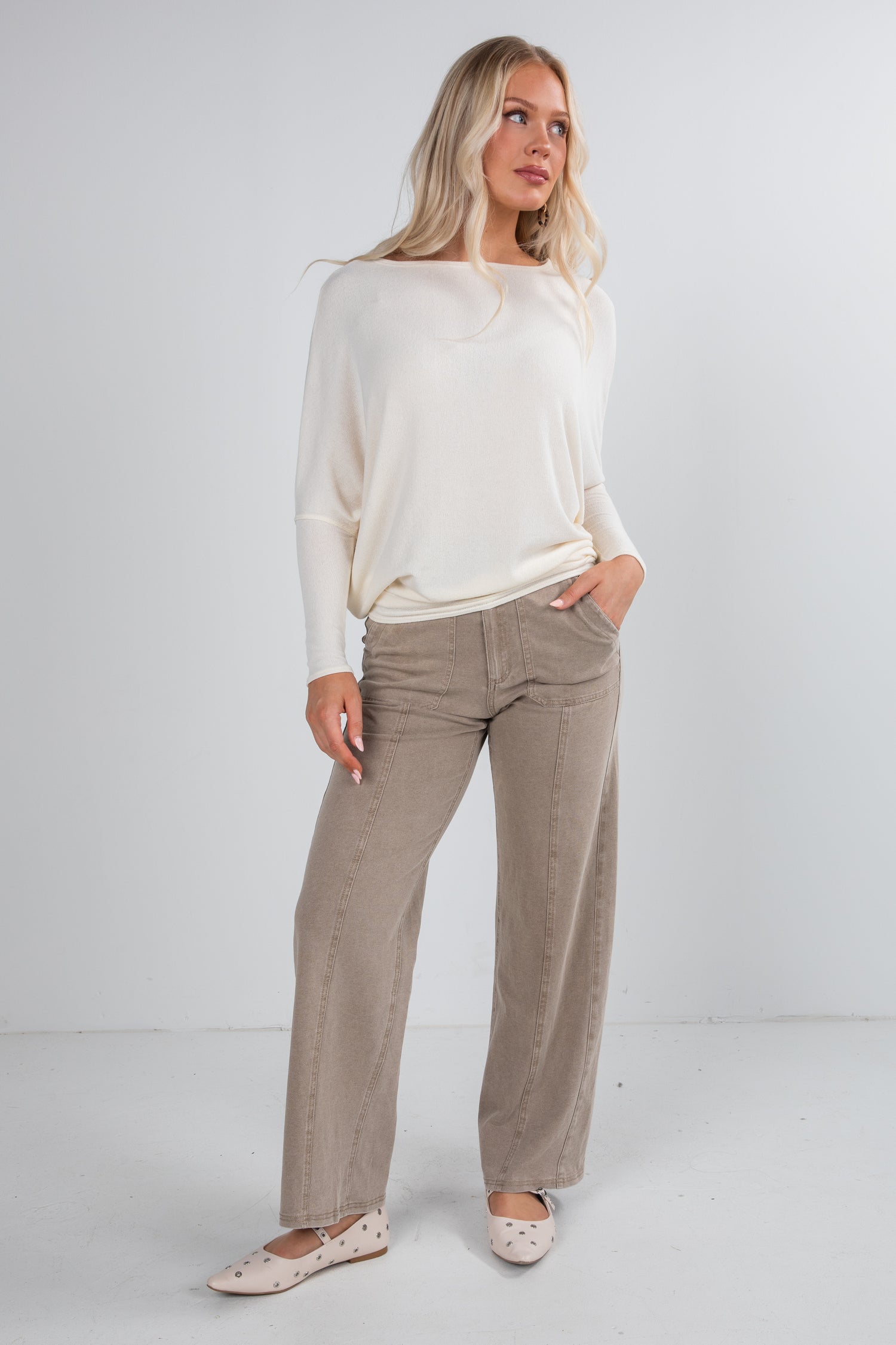 Woman wearing a white top and beige pants on a white background