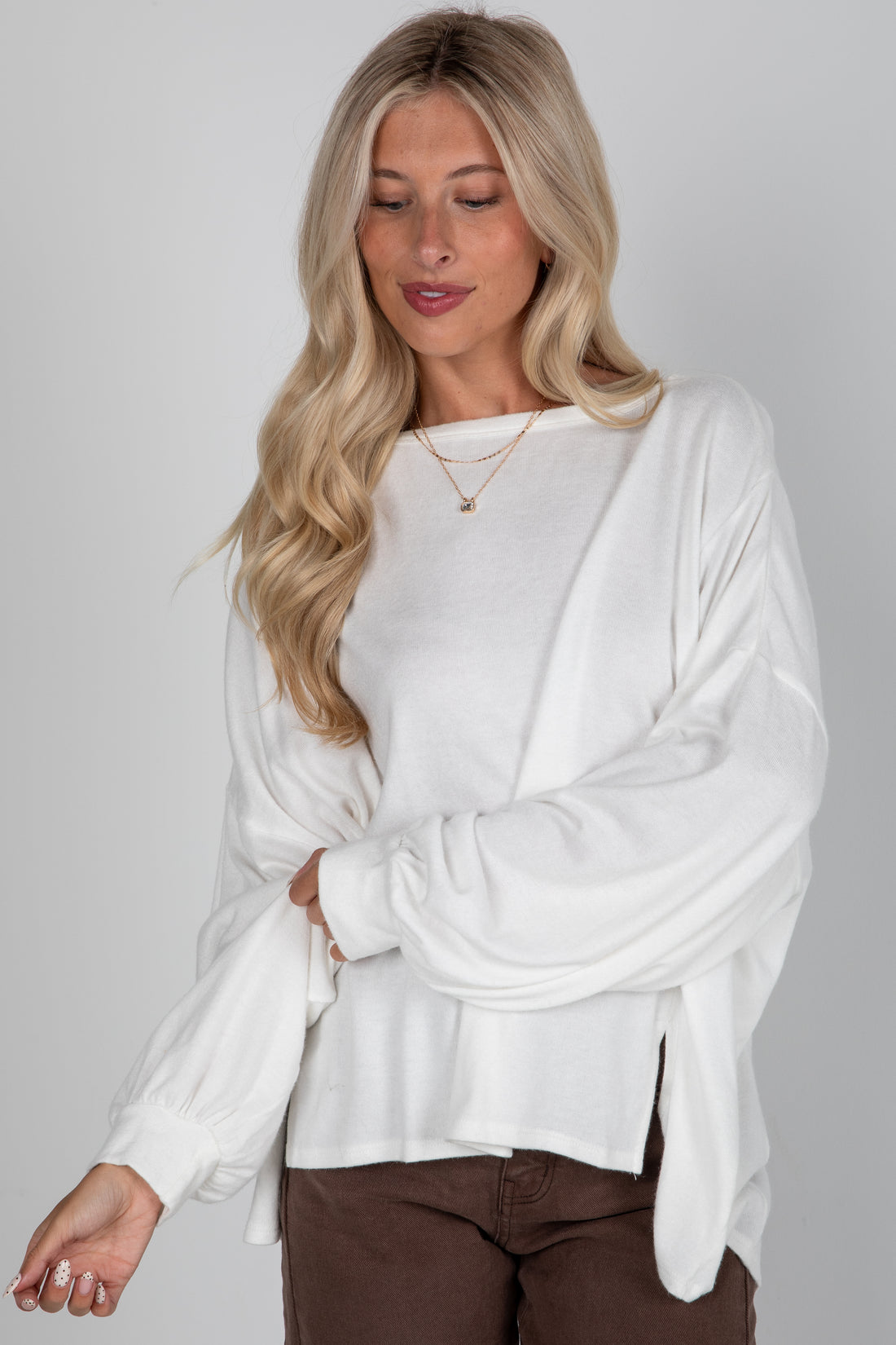 Woman wearing a white long-sleeve top against a plain background