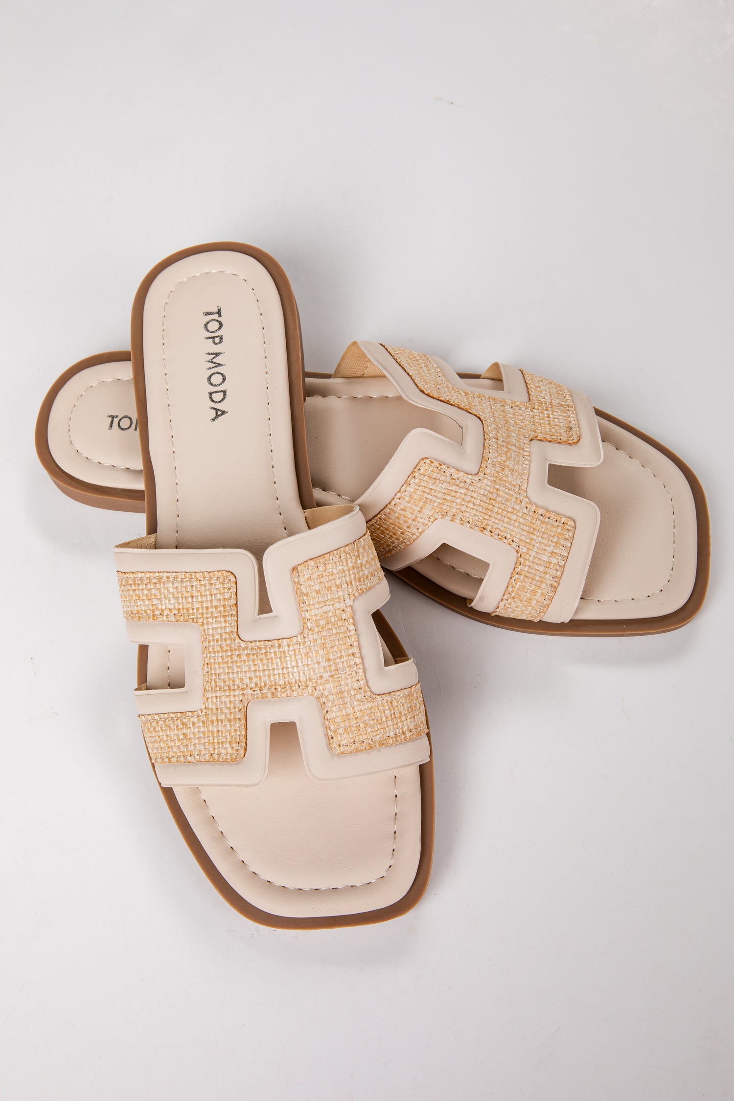 Pair of beige sandals with brown soles on a light gray background