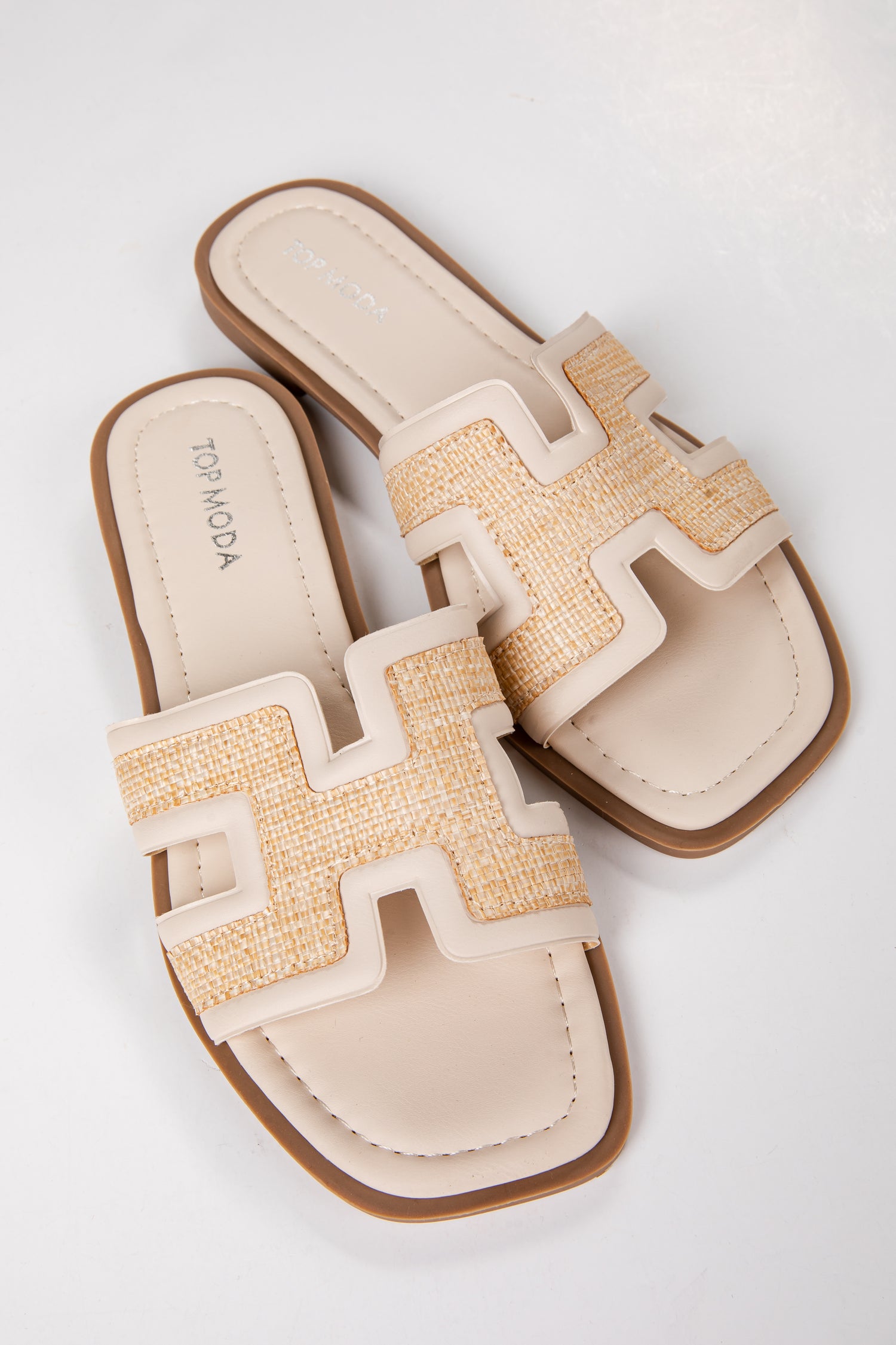 Pair of beige sandals with a textured strap on a white background