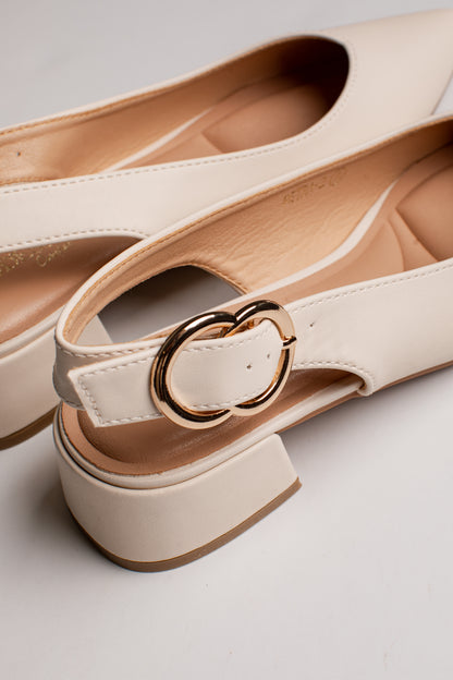 A close-up of a pair of off-white leather slingback flats with chunky block heels and a gold-tone metal ring detail on the strap, set against a clean light gray background.