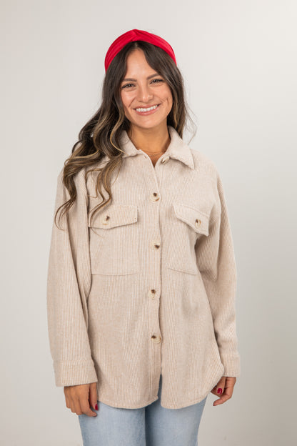 Woman wearing a beige jacket and red headband on a plain background