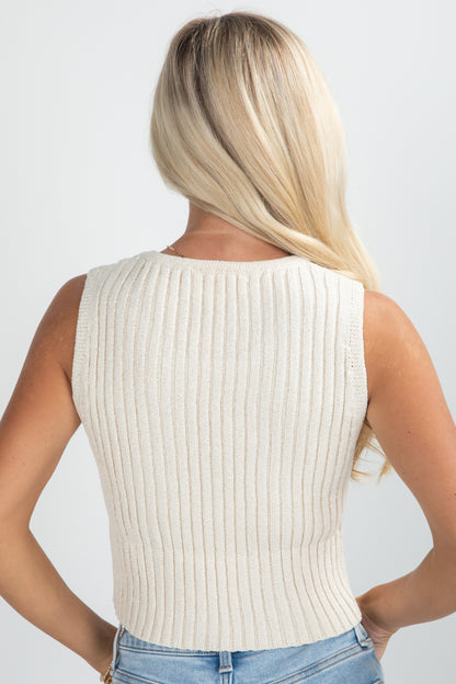 Person wearing a beige ribbed tank top against a plain background
