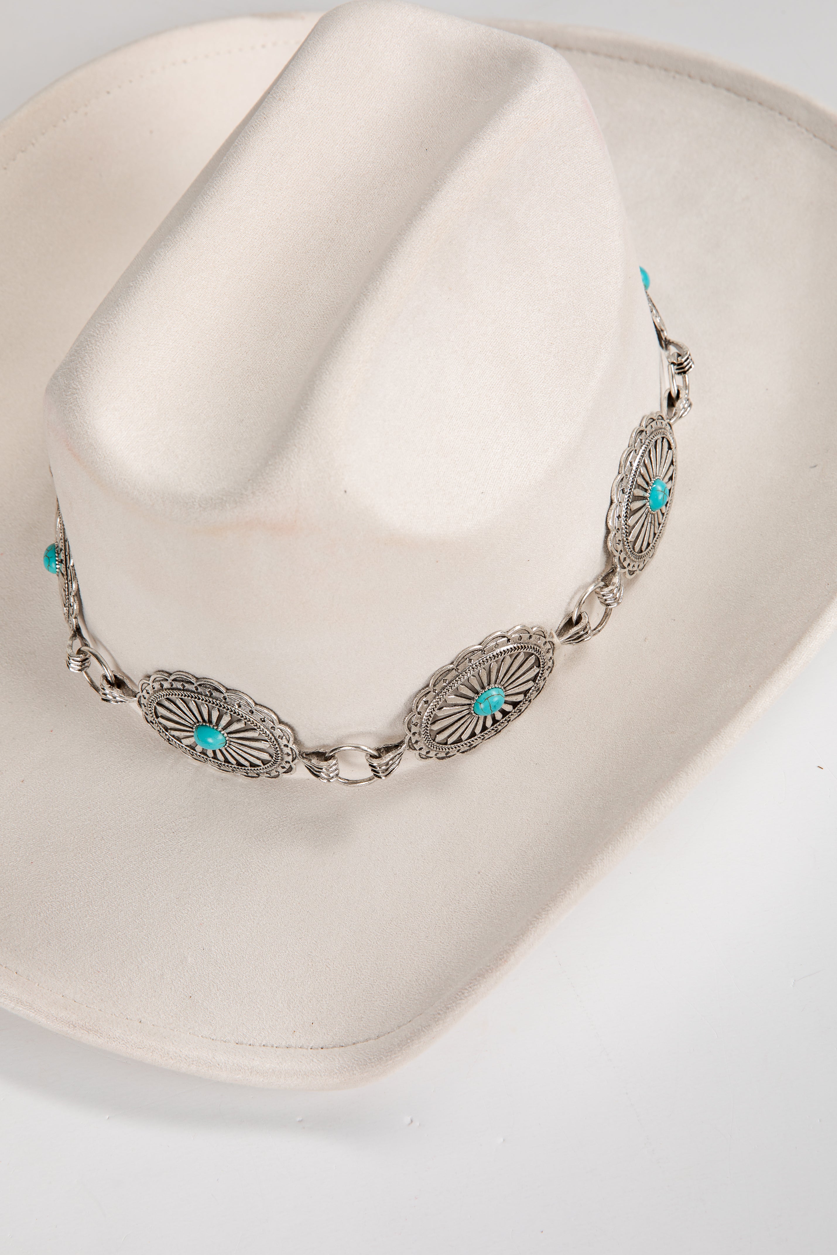 Silver necklace with turquoise stones on a white cowboy hat