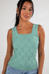 Woman wearing a green sleeveless top against a white background