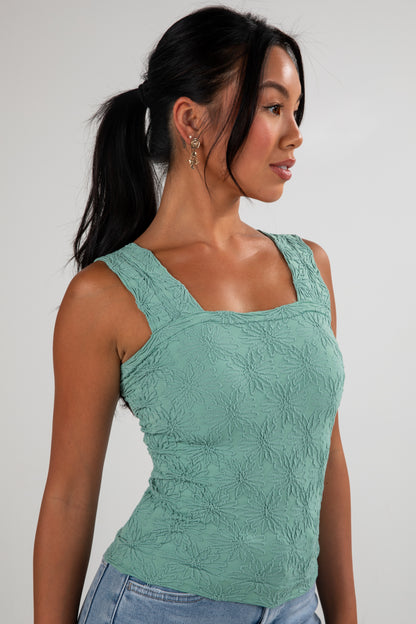 Woman wearing a green textured top against a plain background