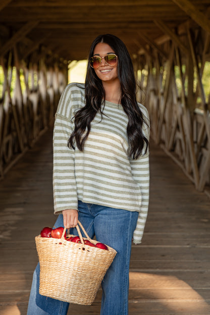 Woman holding a basket of apples on a wooden bridge