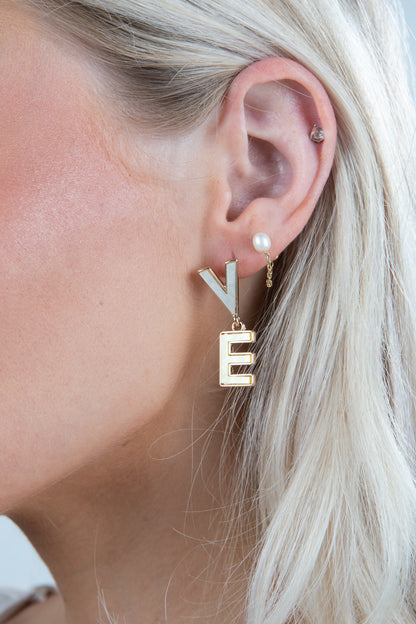 Close-up of a person wearing gold letter &