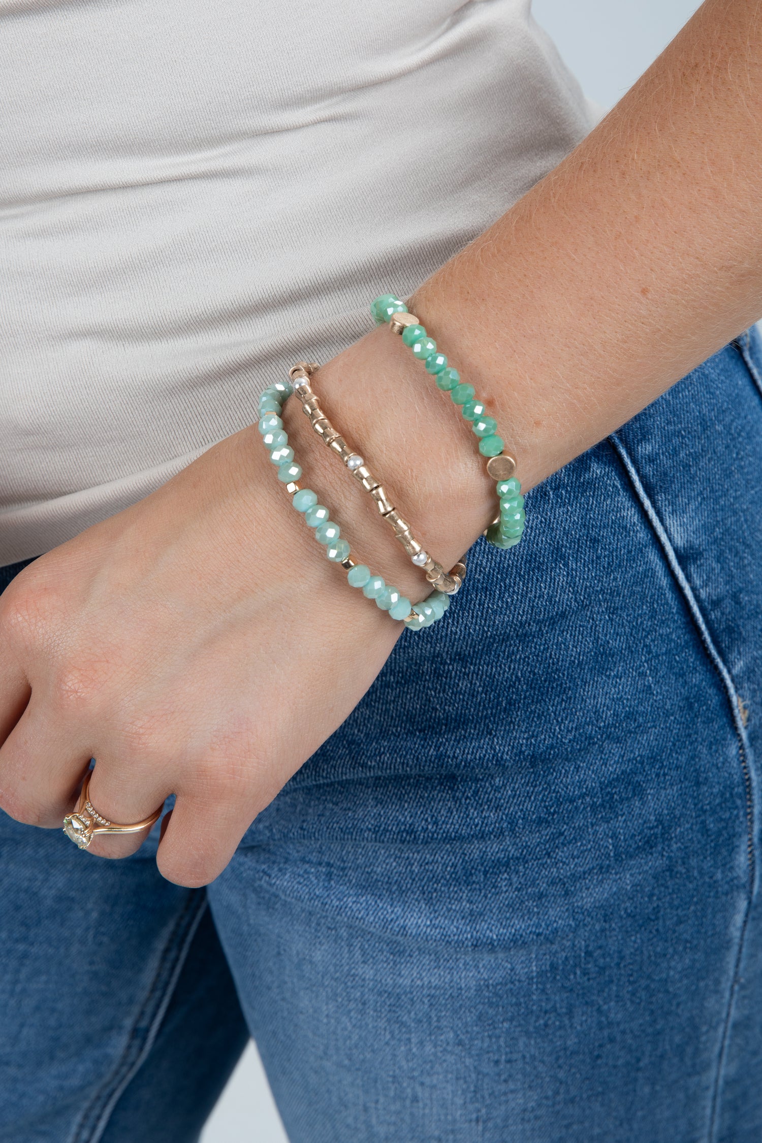 Close-up of a wrist wearing multiple bracelets with a neutral background