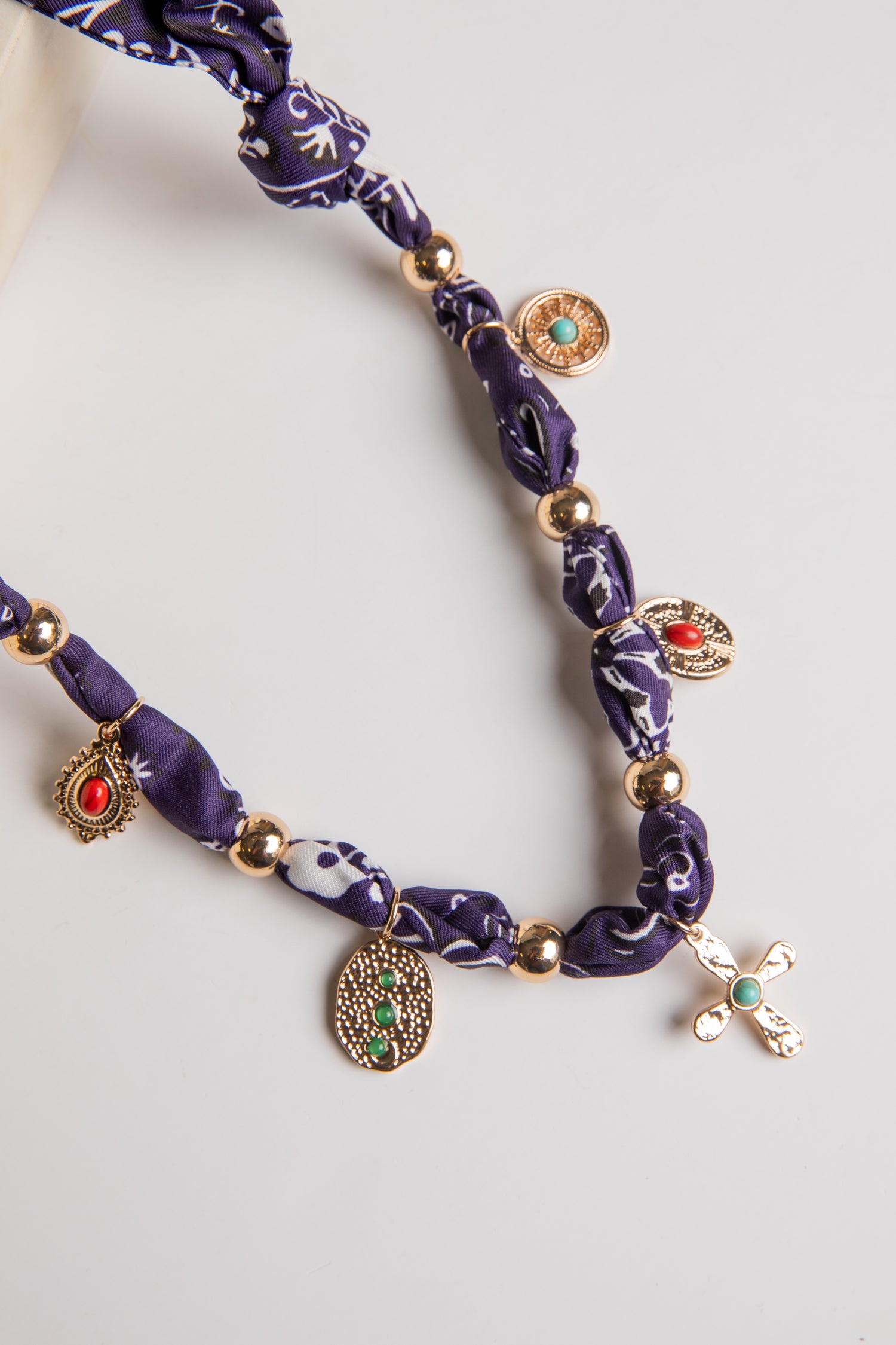 Purple beaded necklace with gold and red accents on a white background