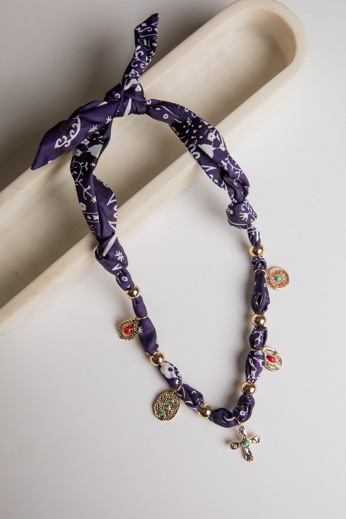 Purple patterned headband with gold beads and charms on a beige surface