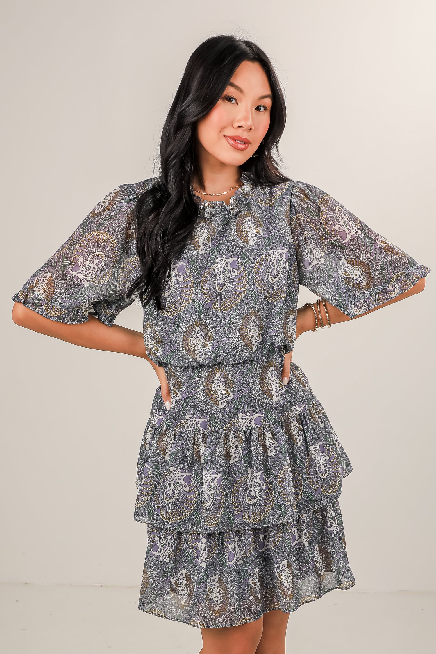 Woman wearing a gray patterned dress against a plain background