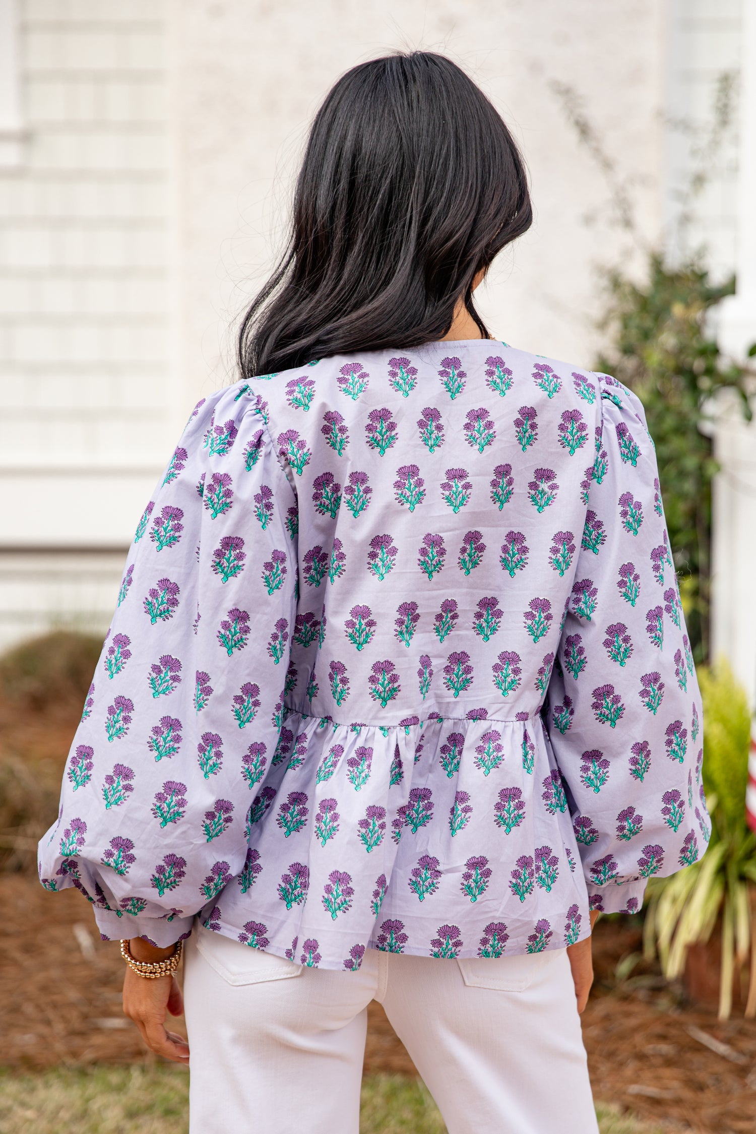 Woman wearing a light purple floral blouse outdoors