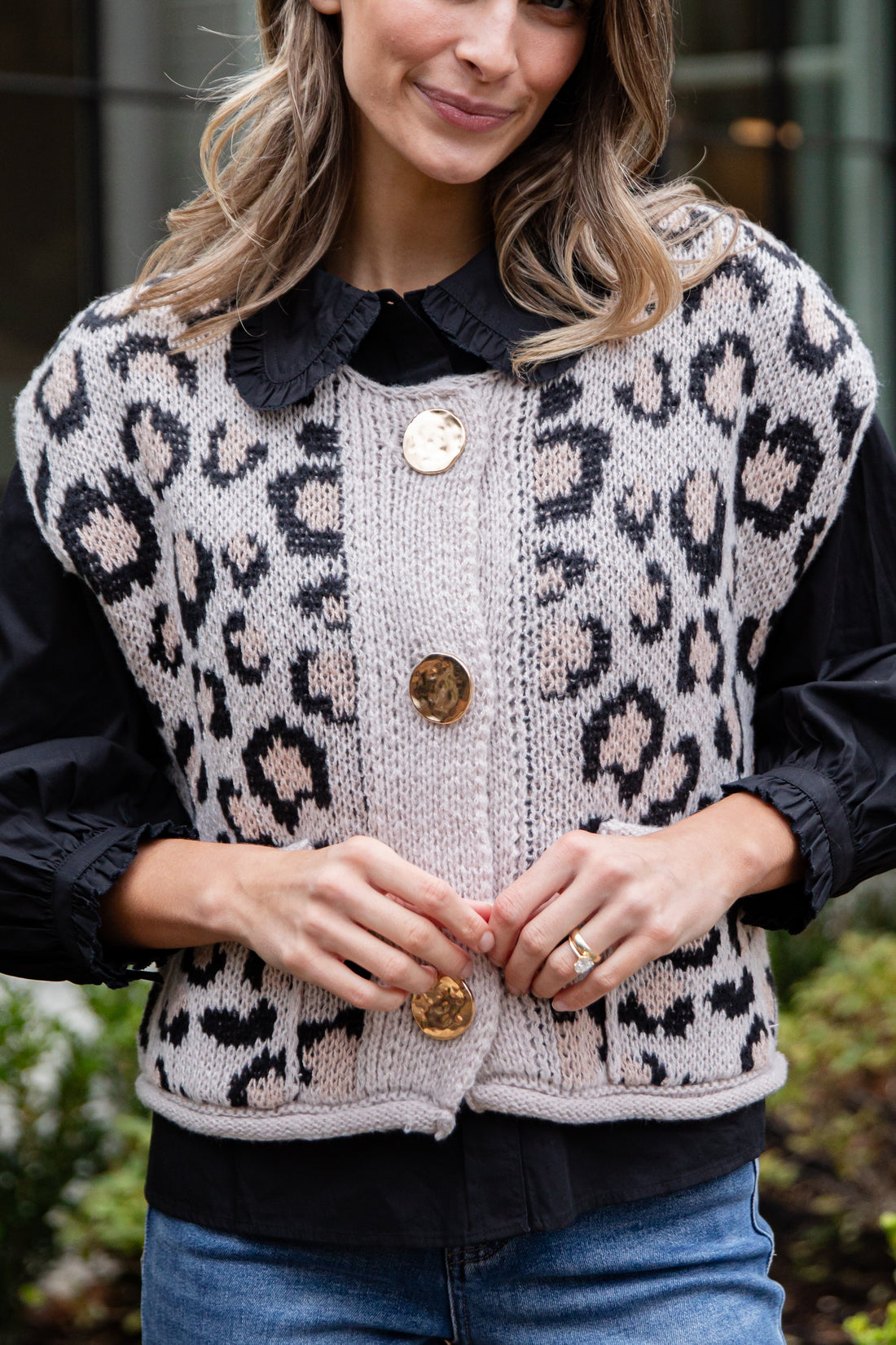 Person wearing a leopard print cardigan with a black collar and buttons.