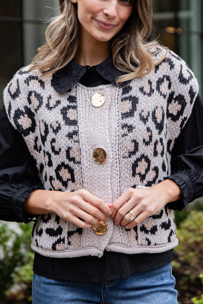 Person wearing a leopard print cardigan with a black collar and buttons.