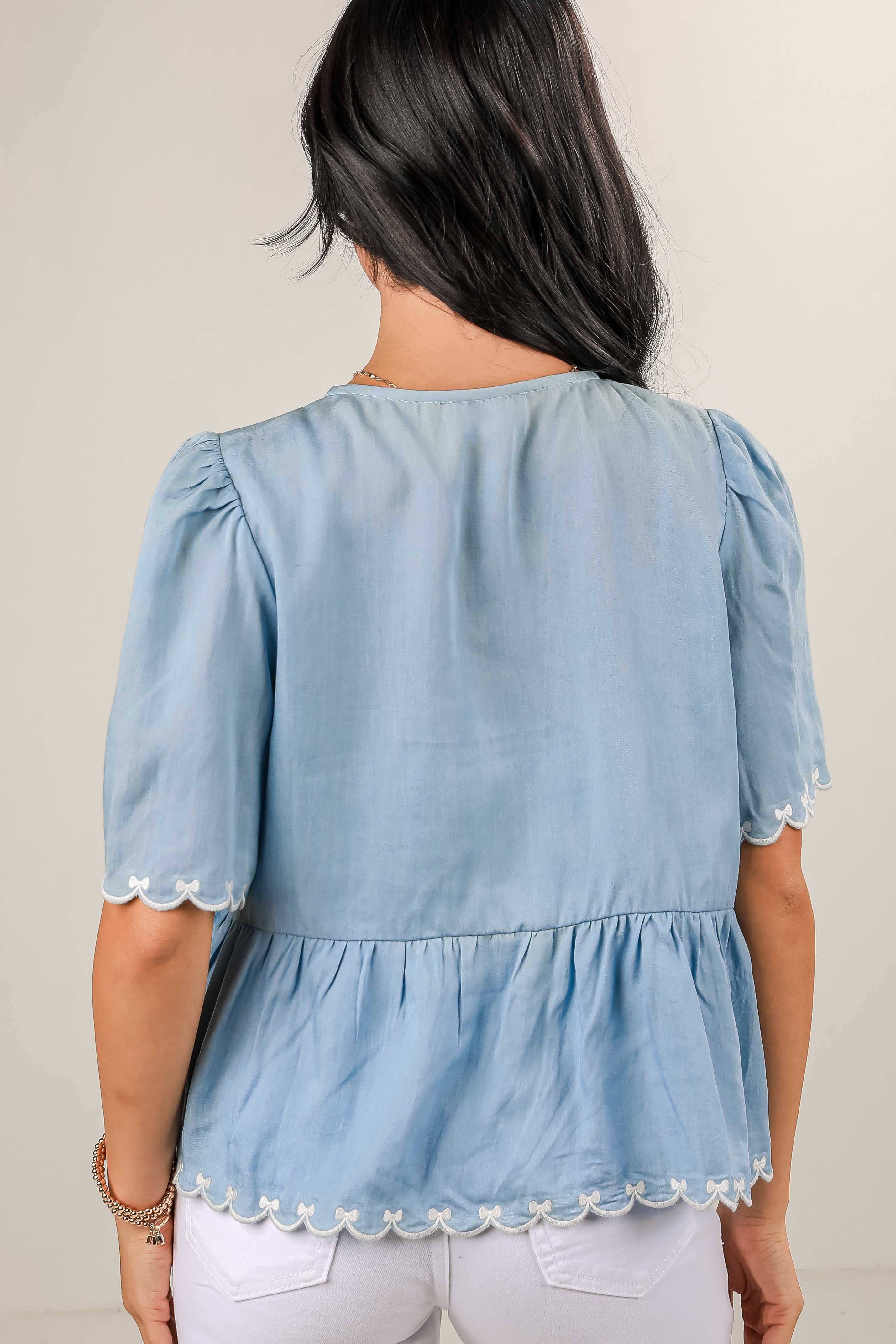 Light blue blouse with lace details worn by a person on a plain background