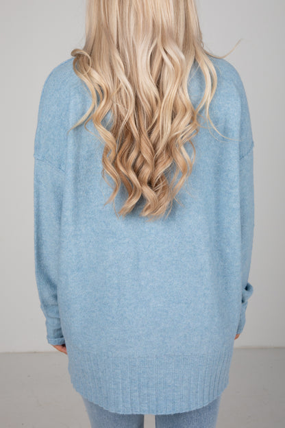 Person wearing a light blue sweater with a plain background