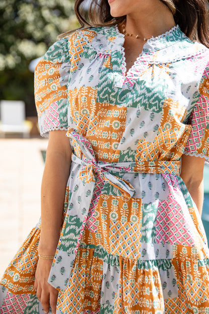 Woman wearing a colorful patterned dress with a blurred outdoor background